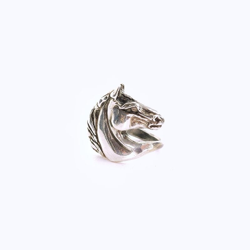 Zilveren ring in de vorm van een gedetailleerd paardenhoofd. De ring is op een witte achtergrond gefotografeerd.