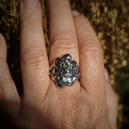 Een handgemaakte zilveren ring met een organisch, golvend design waarin een kleine, ronde, gefacetteerde chrysopraas is gezet.
